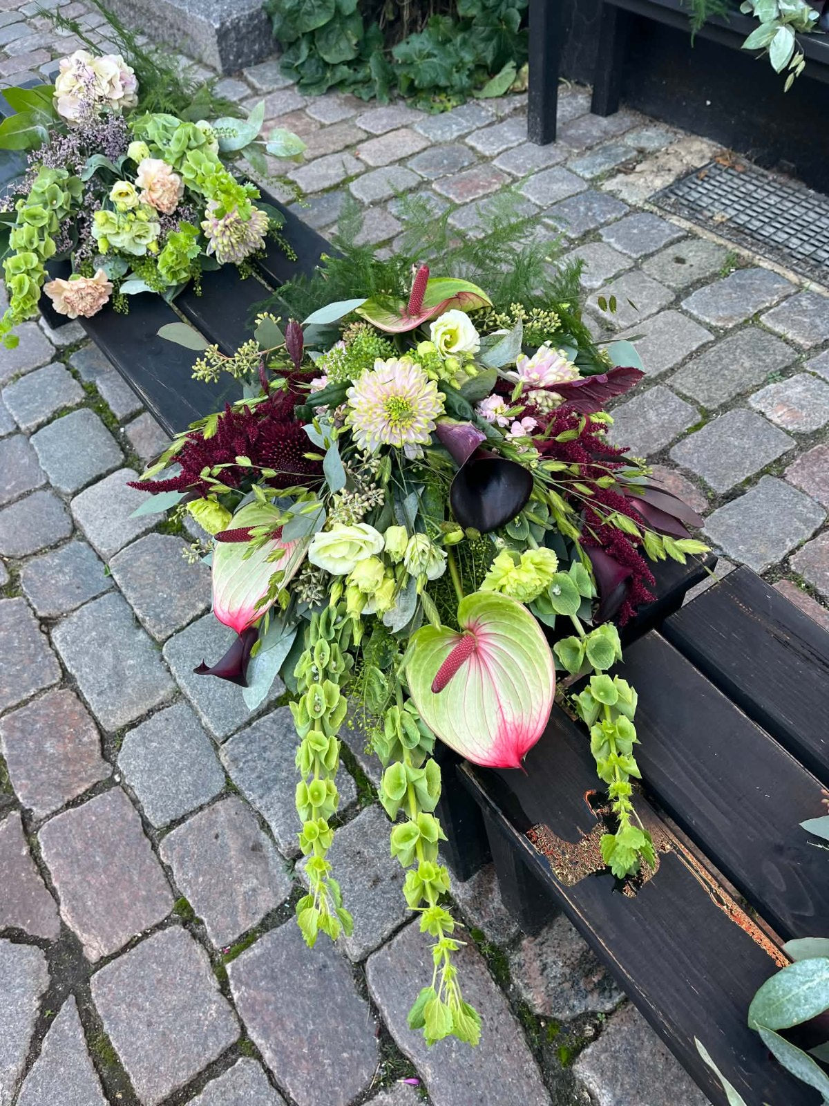 Bårebuket med anthurium, mørkerøde dahlier og hængende grønt